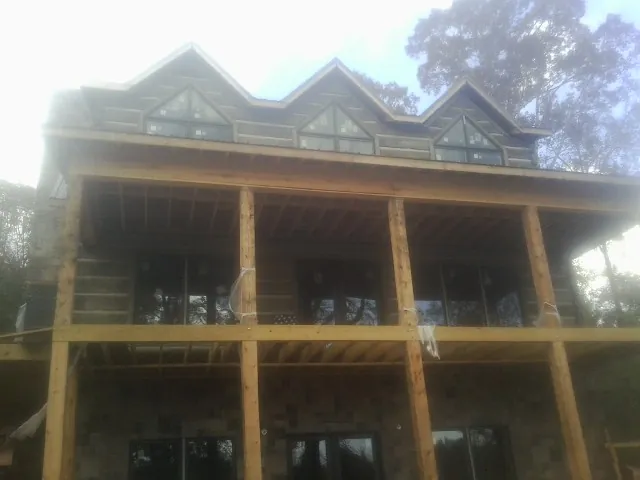 Dormers and porch framing on a large log home under construction — Roof Coating work by our crew in Hempstead