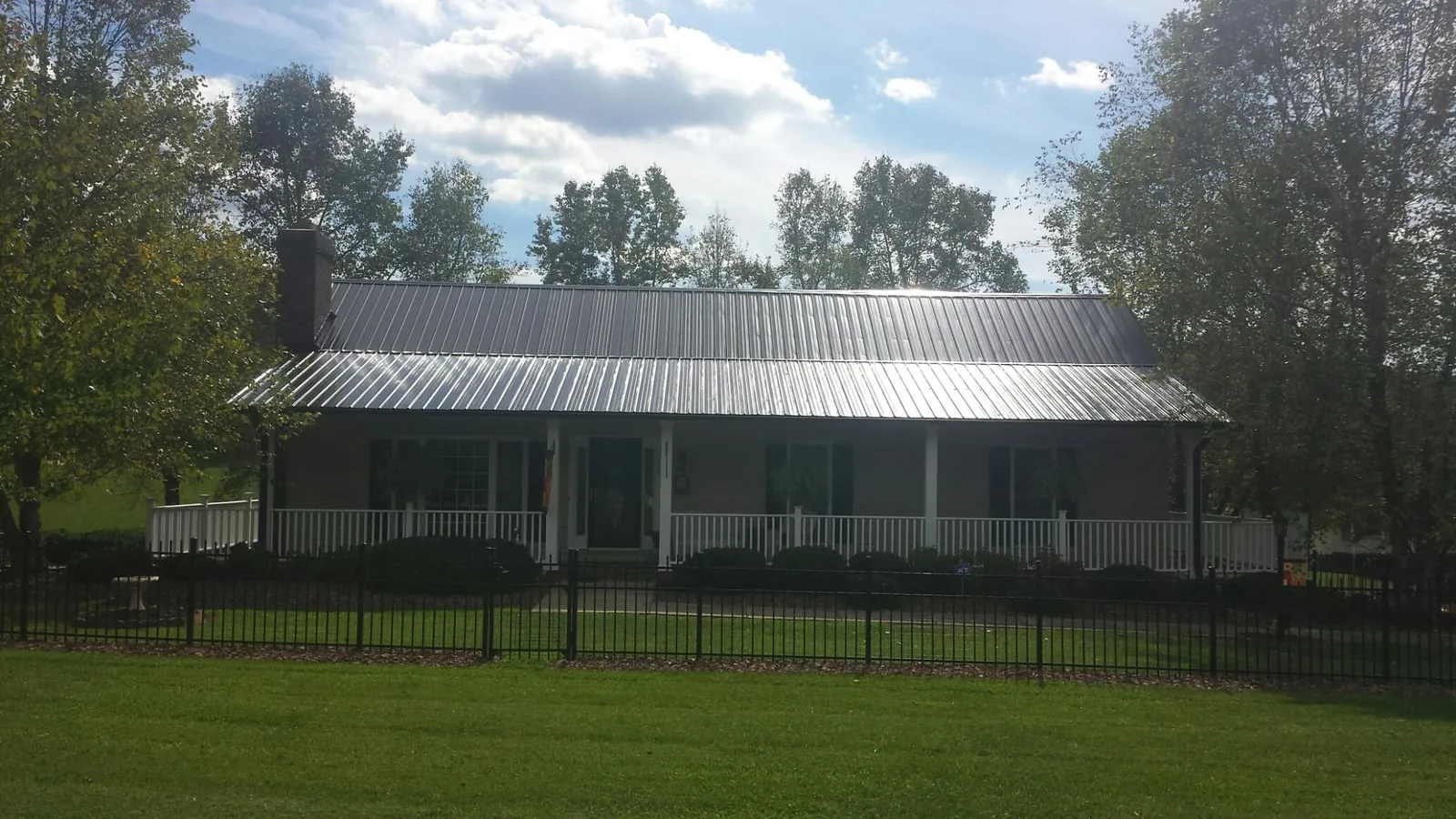 Gray metal roof on a brick ranch with a full width front porch — Gutter Guard Installation work by our crew in Hempstead