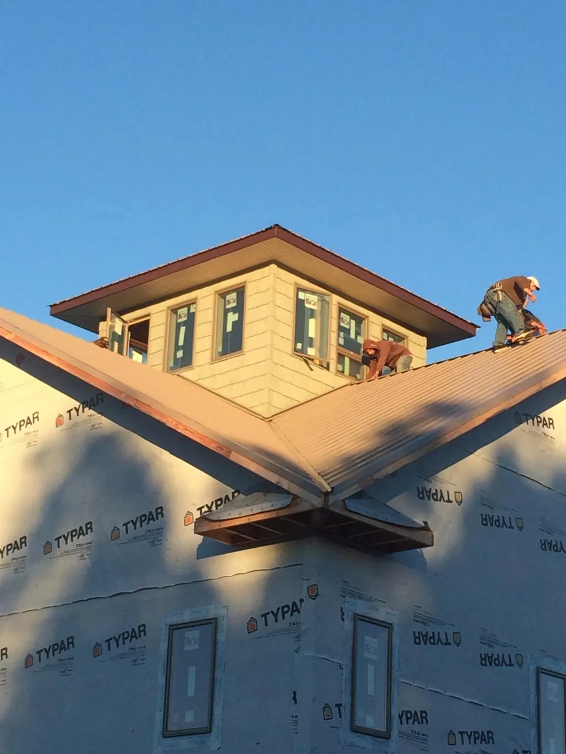 Roofers working around a rooftop cupola on a new metal roof at sunset — Roof Waterproofing in Hempstead by Roofing Brothers